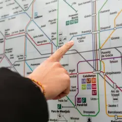 Palec na mapie metra w Barcelonie, wskazujący trasę do lotniska.