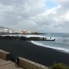 Czarna plaża i kolorowe domy na Teneryfie. Pogoda w październiku bywa zmienna, ale morze wciąż faluje.