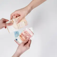 Dwie ręce przekazują sobie banknoty euro. W Holandii obowiązuje euro, więc to typowy widok.