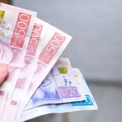 Dłoń trzyma banknoty 500 koron szwedzkich. To właśnie jaka waluta jest w Szwecji.