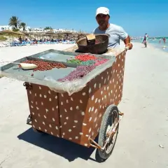 Sprzedawca na plaży w Tunezji oferuje słodycze. Może to być okazja do wymiany drobnych na pyszności, bo tunezja waluta to dinar.
