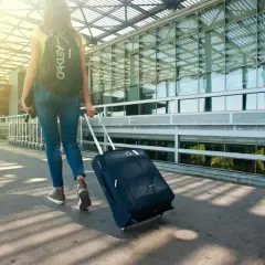 Kobieta z walizką i plecakiem idzie do terminalu. Pamiętaj, czego nie wolno zabrać do Turcji, by podróż była udana.