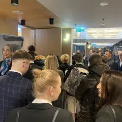 Uśmiechnięta stewardessa LOT Cabin Crew wita grupę osób. Marzenie o pracy w przestworzach zaczyna się tutaj.