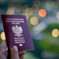 Polski paszport w dłoni, gotowy na wakacje bez paszportu w strefie Schengen. Rozmyte światła w tle tworzą magiczny nastrój.