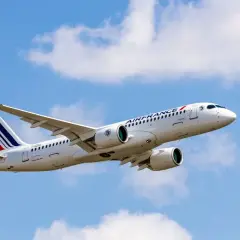 Airbus A220-300 linii Air France wzbija się w błękitne niebo z białymi chmurami.