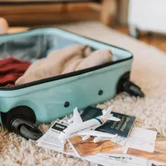 Otwarta walizka z ubraniami, obok paszport, bilety i model samolotu. Gotowi na podróż z Electra Airways!
