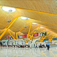 Nowoczesna architektura lotniska Madryt z żółtymi podporami i drewnianym sufitem.