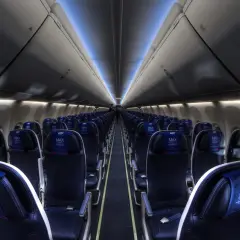 Wnętrze samolotu Boeing 737 MAX 8 LOT, rzędy ciemnych foteli z niebieskimi zagłówkami z logo LOT MAX.