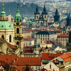 Widok panoramy Pragi z charakterystycznymi wieżami i zielonymi kopułami.