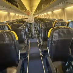 Wnętrze samolotu Boeing 737 z rzędami czarnych siedzeń z żółtymi zagłówkami. Zastanawiasz się, boeing 737 ile miejsc?