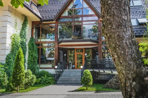 Elegancki hotel Belvedere Resort & Spa z imponującą szklaną fasadą, otoczony zielenią.