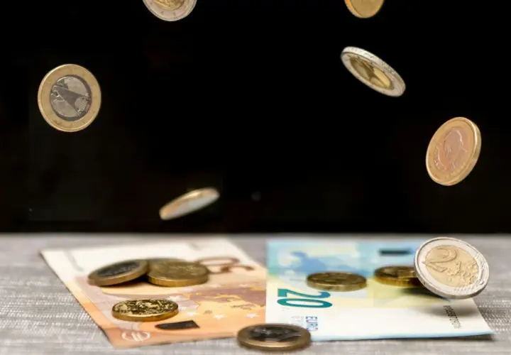 Monety euro spadają na banknoty 50 i 20 euro. To symboliczna scena pokazująca portugalia waluta w ruchu.