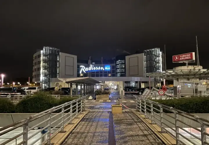 Nocny widok na hotel Radisson Blu Hamburg. Widać logo hotelu, znak Turkish Airlines i wejście.
