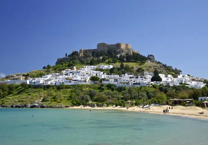 Majowa pogoda na Rodos zachwyca: białe domki Lindos, zamek na wzgórzu i turkusowe morze. Idealny czas na plażowanie.