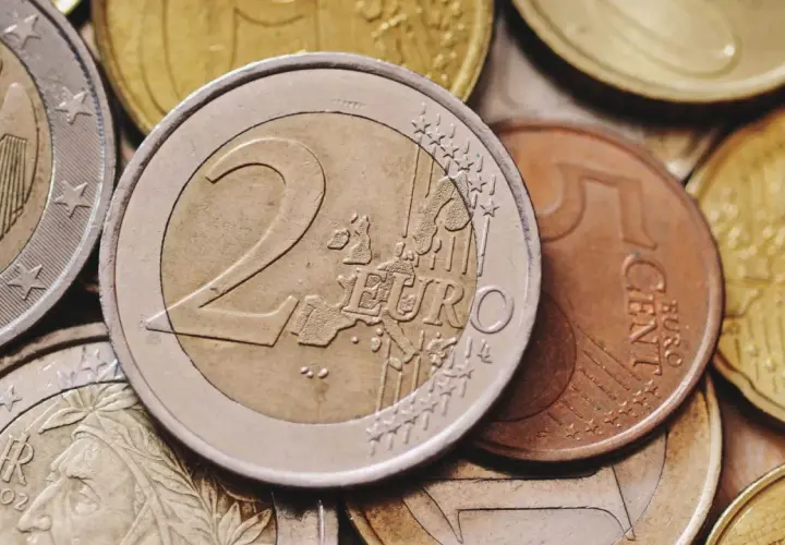 Zbliżenie na stos monet euro, w tym monety 2 euro i 5 centów.