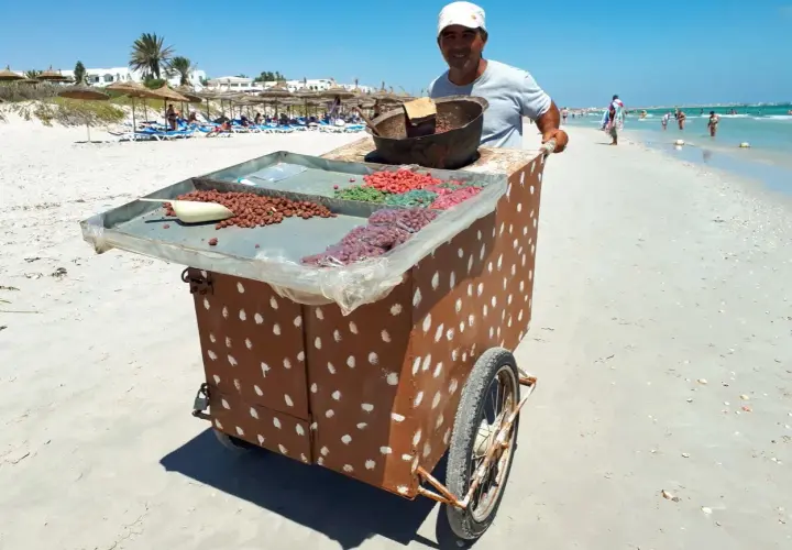 Sprzedawca na plaży w Tunezji oferuje słodycze. Może to być okazja do wymiany drobnych na pyszności, bo tunezja waluta to dinar.