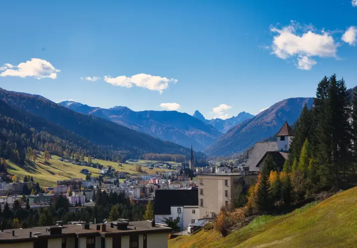 Widok na miasteczko w dolinie otoczonej górami. W oddali widać kościół z wieżą. Tak właśnie wygląda Davos.