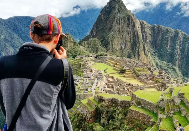 Niesamowita wycieczka do Peru! Turysta z aparatem podziwia Machu Picchu, majestatyczne ruiny Inków w otoczeniu gór.