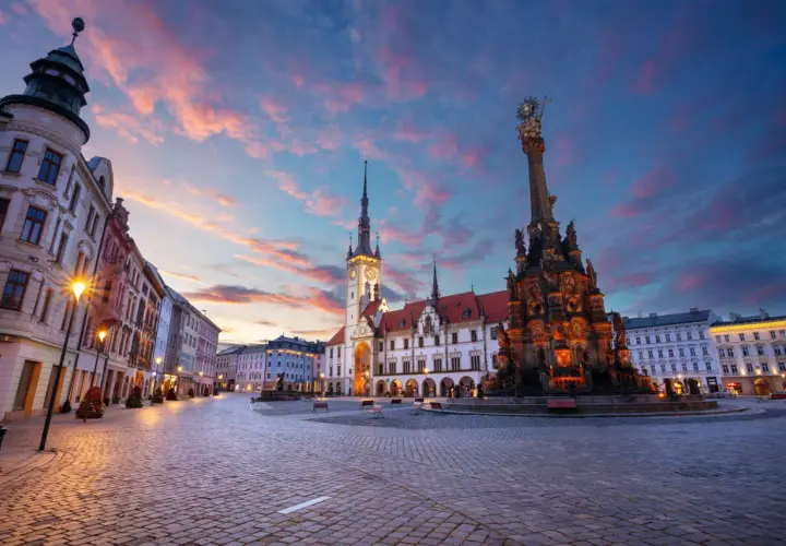 Zachód słońca nad pięknym rynkiem w Olomoucu, z widokiem na zabytkowy ratusz i Kolumnę Trójcy Świętej. Dolina Morawy wita o zmierzchu.