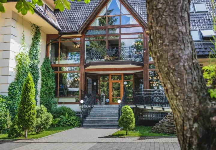Elegancki hotel Belvedere Resort & Spa z imponującą szklaną fasadą, otoczony zielenią.