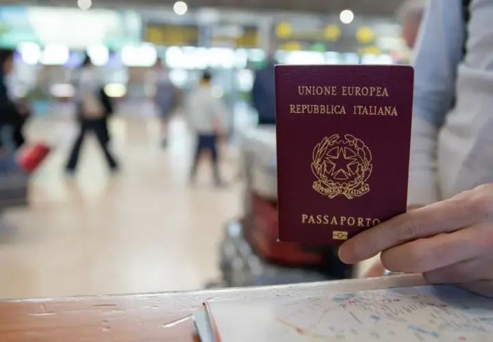 Włoski paszport w dłoni, na tle lotniska. Czy do Finlandii potrzebny jest paszport? Tak, jeśli nie jesteś obywatelem UE.
