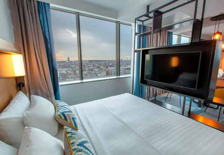 Pokój w hotelu Courtyard w Katowicach z widokiem na miasto. Łóżko, telewizor i zasłony.