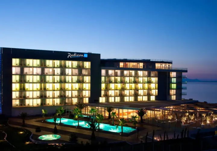 Hotel Radisson Blu Split nocą, z podświetlonymi oknami, basenami i palmami.