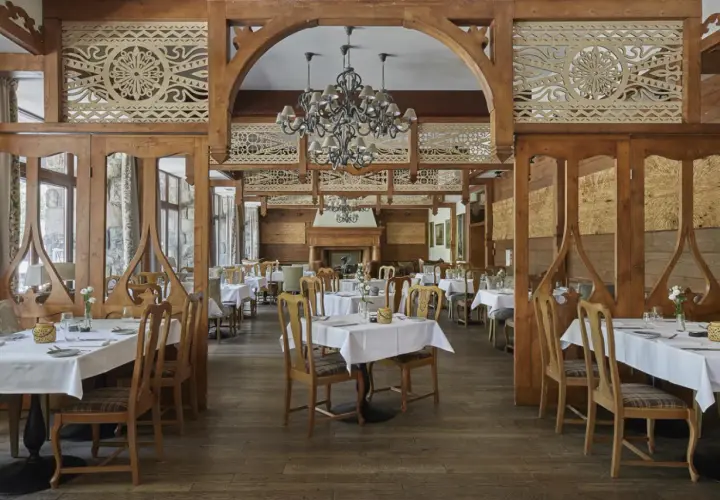 Elegancka restauracja w hotelu 5 gwiazdkowym, z drewnianymi zdobieniami i przytulnym kominkiem.