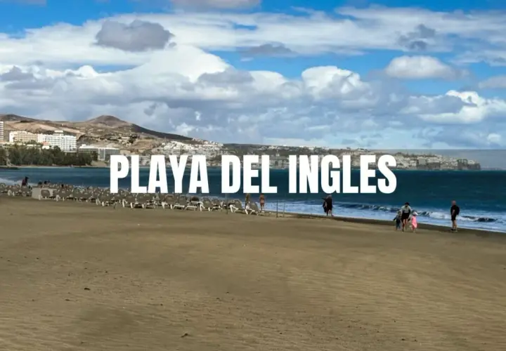 Piękna plaża Playa del Inglés z rzędami leżaków i kilkoma spacerującymi ludźmi. W tle widać hotele i góry.