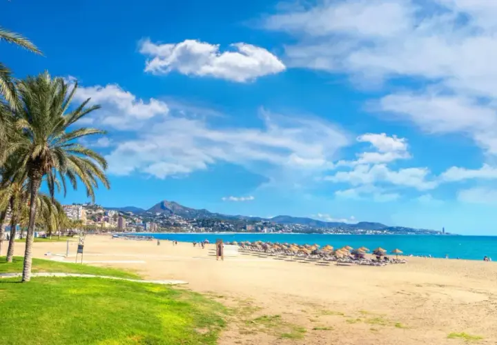 Malaga w maju: słoneczna plaża z palmami, turkusowe morze i góry w tle. Idealna pogoda na wypoczynek.