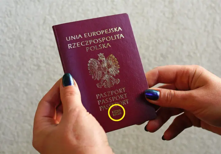 Dłonie trzymają polski paszport biometryczny z symbolem aparatu.
