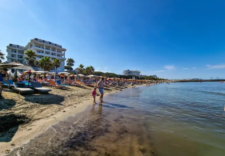 Słoneczna plaża w Golem, Albania, z leżakami, parasolami i hotelami. Idealne miejsce na wakacje, jedna z głównych atrakcji.