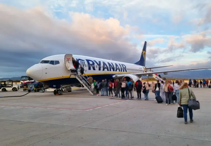 Pasażerowie wsiadają do samolotu Ryanair. W tle chmury i góry. To jak faktura za podróż, która właśnie się zaczyna.