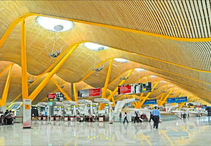 Nowoczesna architektura lotniska Madryt z żółtymi podporami i drewnianym sufitem.