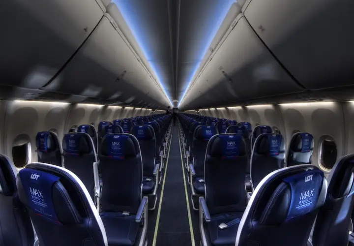 Wnętrze samolotu Boeing 737 MAX 8 LOT, rzędy ciemnych foteli z niebieskimi zagłówkami z logo LOT MAX.