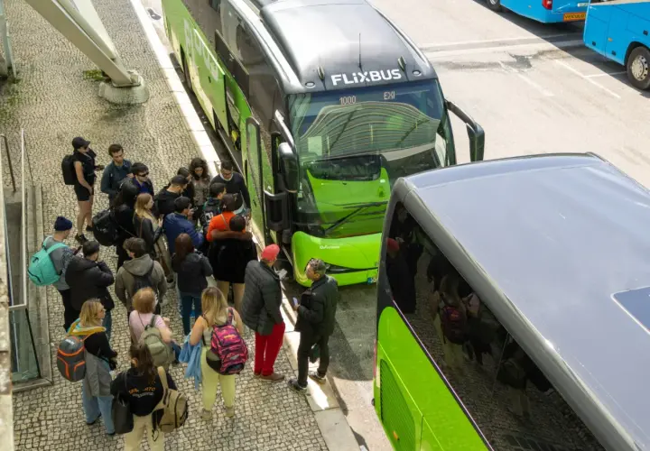 Grupa ludzi czeka na zielonego Flixbusa, szukając okazji na podróż.