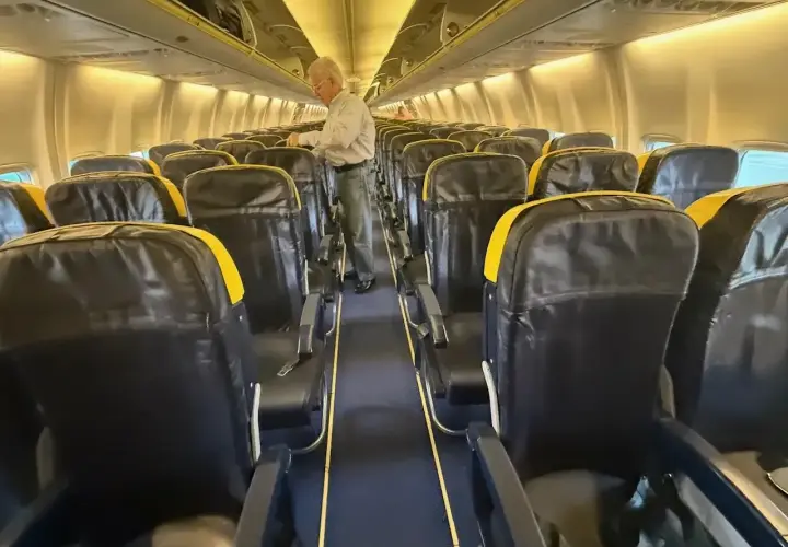 Wnętrze samolotu Boeing 737 z rzędami czarnych siedzeń z żółtymi zagłówkami. Zastanawiasz się, boeing 737 ile miejsc?