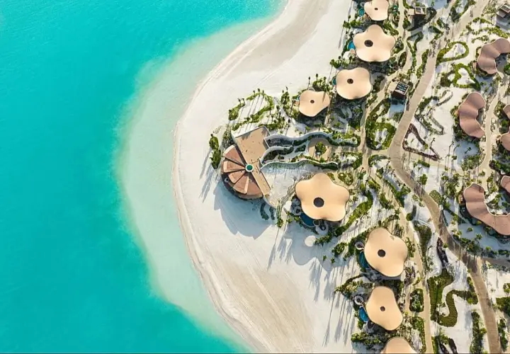 Widok z lotu ptaka na luksusowy hotel Four Seasons z unikalnymi, kwiatowymi dachami, położony przy turkusowym morzu i białej plaży.