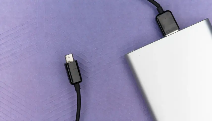 Srebrny powerbank, niezbędny w bagażu podręcznym, gotowy do ładowania urządzeń w podróży.