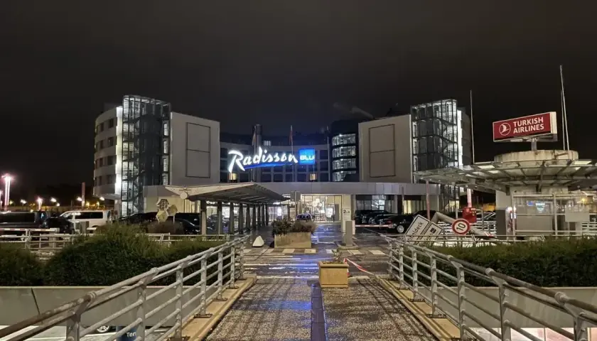 Nocny widok na hotel Radisson Blu Hamburg. Widać logo hotelu, znak Turkish Airlines i wejście.