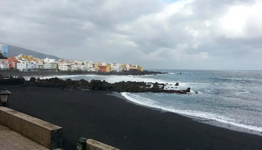Czarna plaża i kolorowe domy na Teneryfie. Pogoda w październiku bywa zmienna, ale morze wciąż faluje.