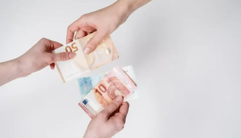 Dwie ręce przekazują sobie banknoty euro. W Holandii obowiązuje euro, więc to typowy widok.