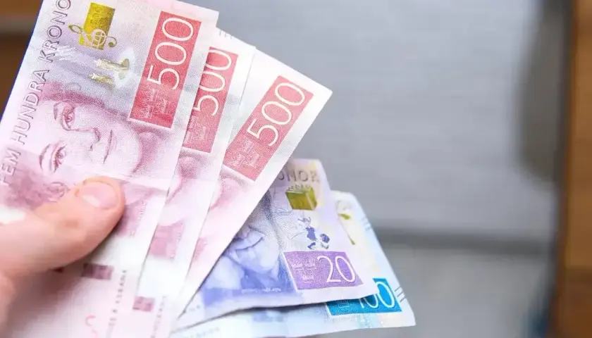Dłoń trzyma banknoty 500 koron szwedzkich. To właśnie jaka waluta jest w Szwecji.