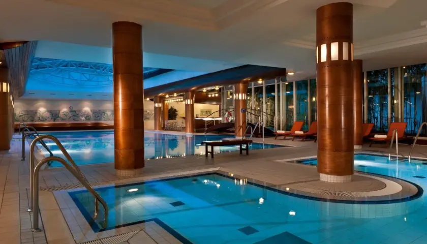 Basen hotelowy z leżakami i dekoracjami ściennymi.