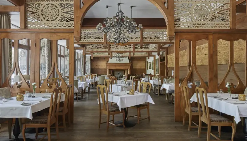 Elegancka restauracja w hotelu 5 gwiazdkowym, z drewnianymi zdobieniami i przytulnym kominkiem.