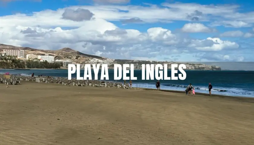 Piękna plaża Playa del Inglés z rzędami leżaków i kilkoma spacerującymi ludźmi. W tle widać hotele i góry.