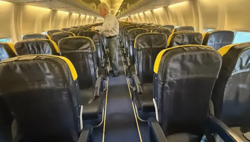 Wnętrze samolotu Boeing 737 z rzędami czarnych siedzeń z żółtymi zagłówkami. Zastanawiasz się, boeing 737 ile miejsc?