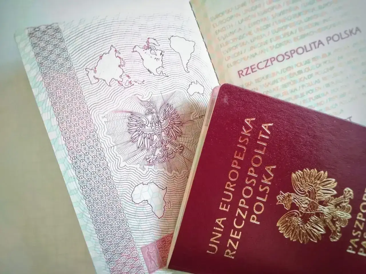 Polski paszport z godłem orła i mapą świata. Czy do Szwecji potrzebny jest paszport? Tak, jeśli podróżujesz spoza strefy Schengen.