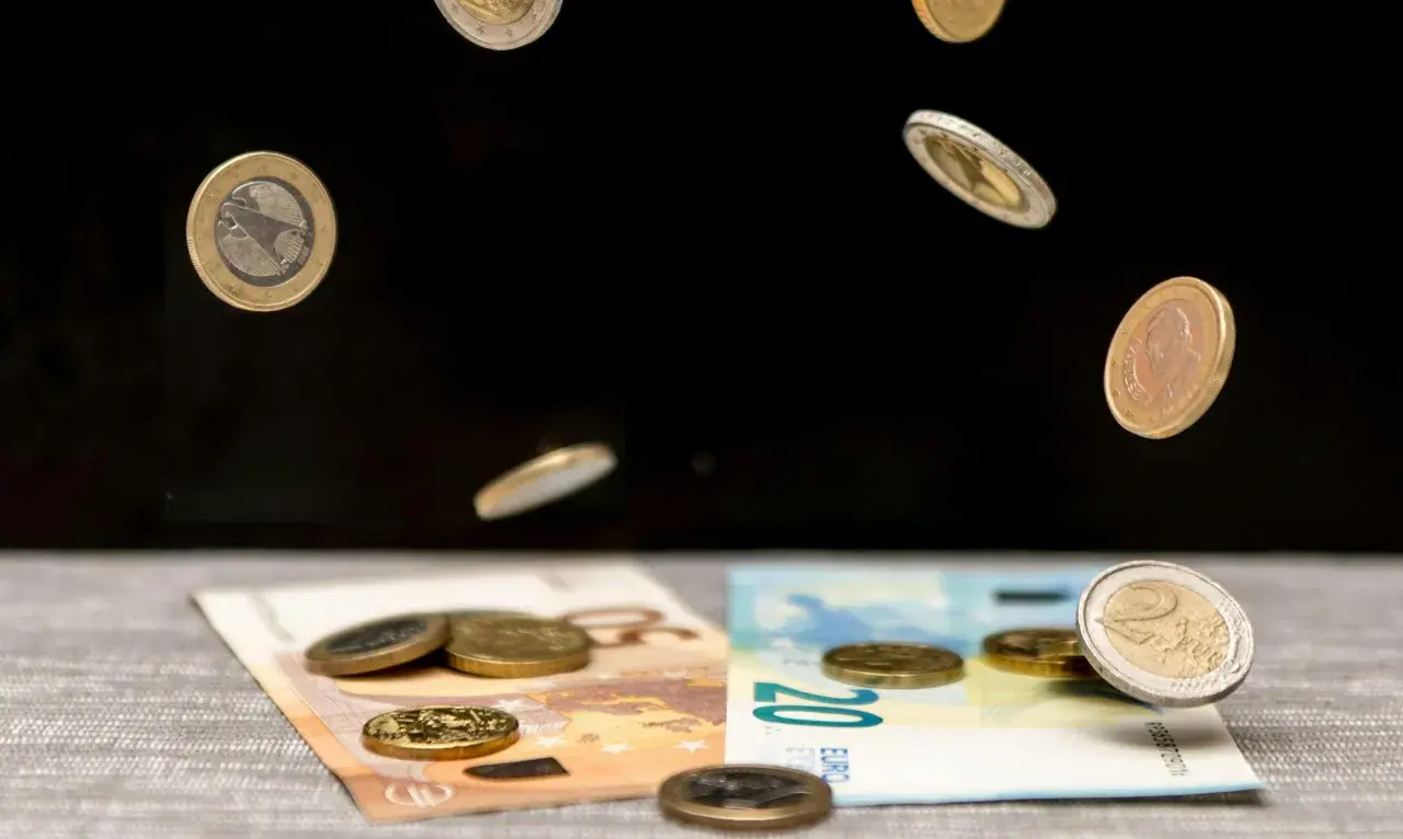 Monety euro spadają na banknoty 50 i 20 euro. To symboliczna scena pokazująca portugalia waluta w ruchu.