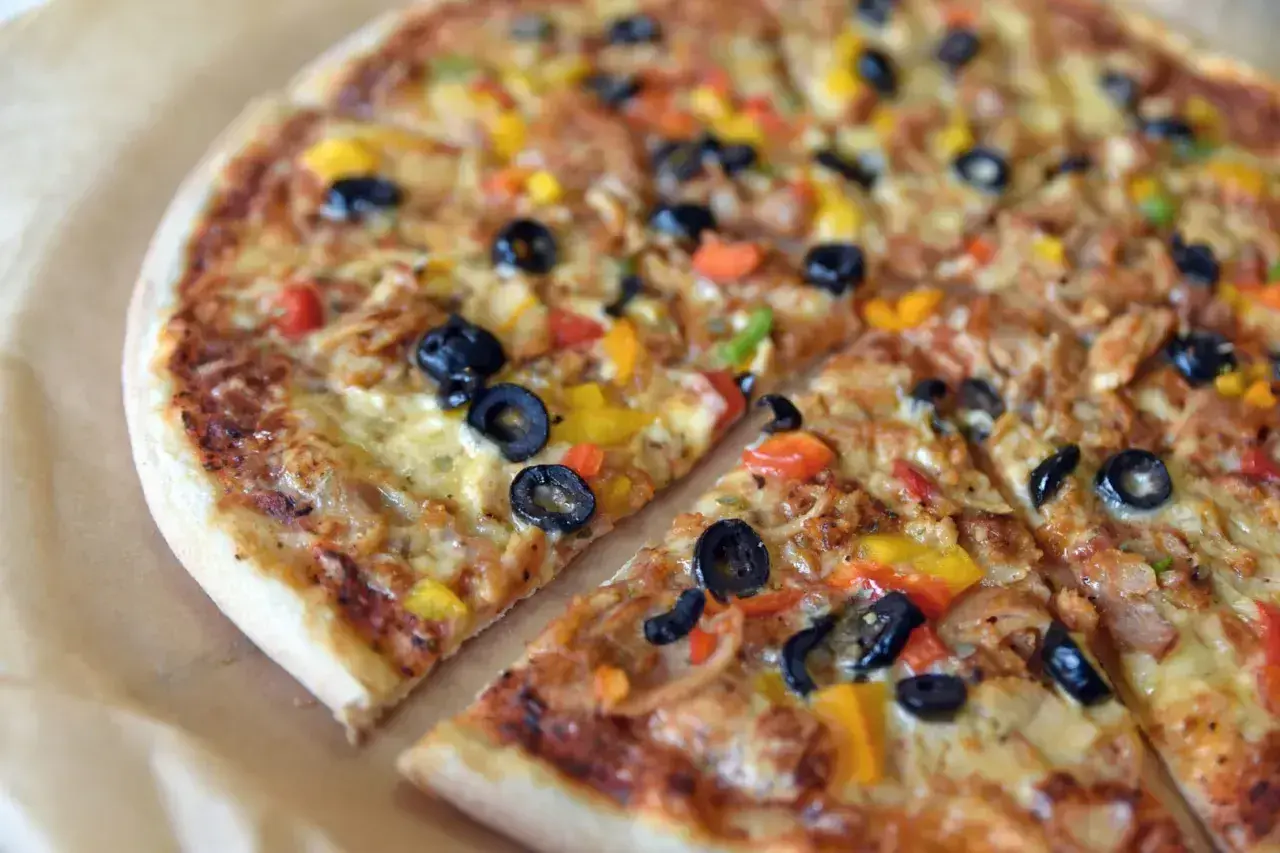 Kolorowa pizza z oliwkami, papryką i kurczakiem. Różne rodzaje pizzy mogą zawierać podobne, pyszne składniki.